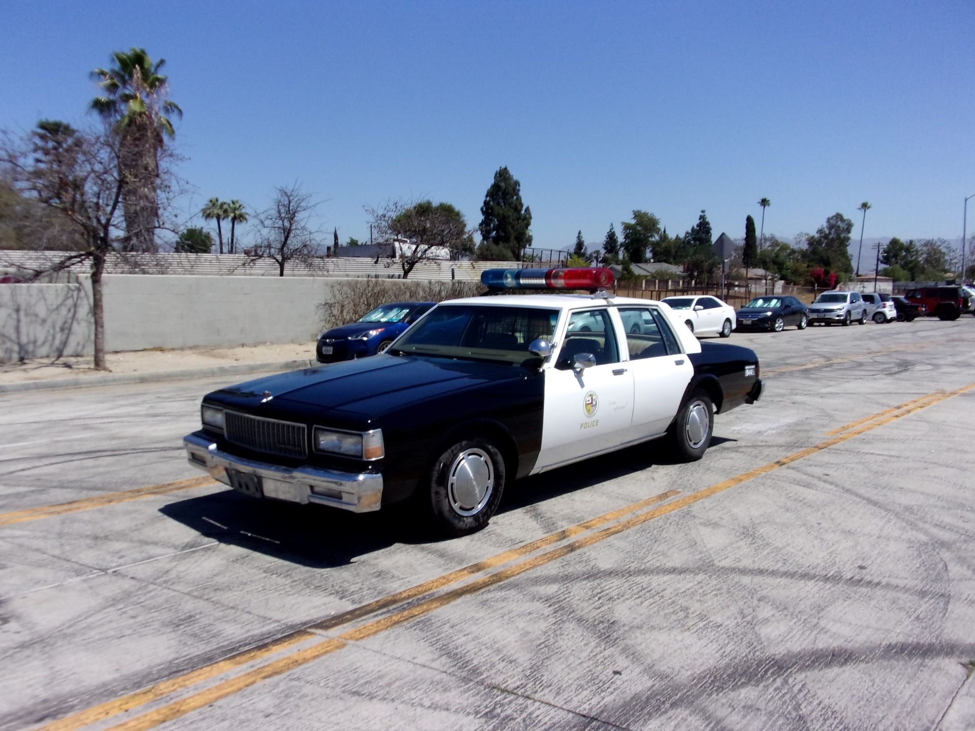 a black and white police car is parked in a parking lot and ready to install a pod rig for film shooting.