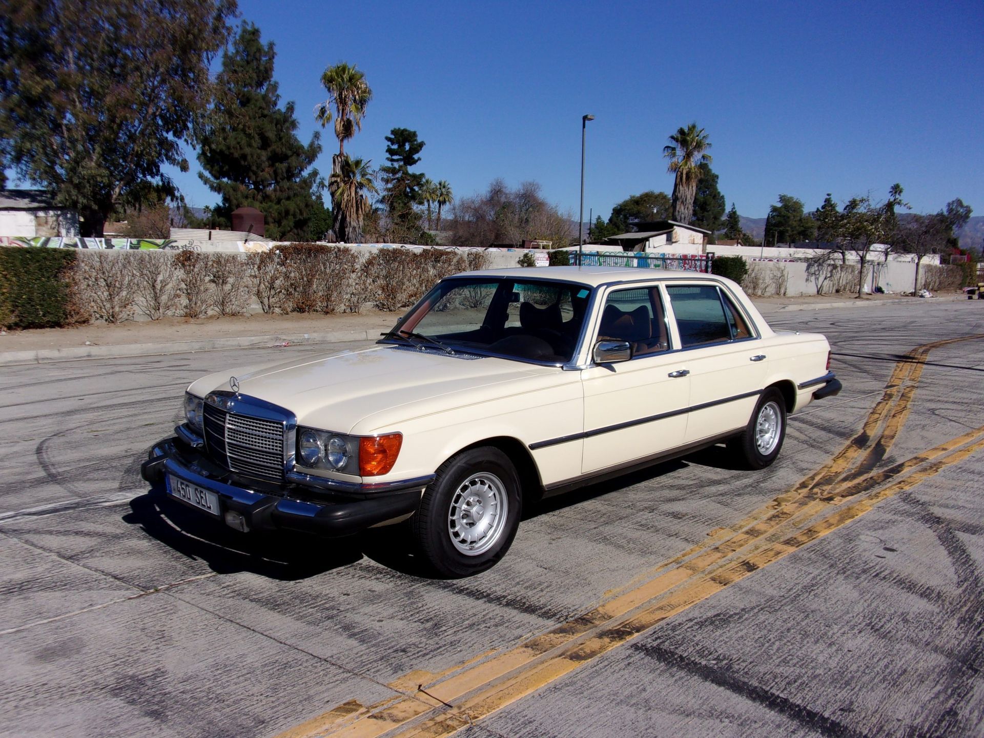 a white mercedes benz is parked in a parking lot and ready to install a pod rig for film shooting.