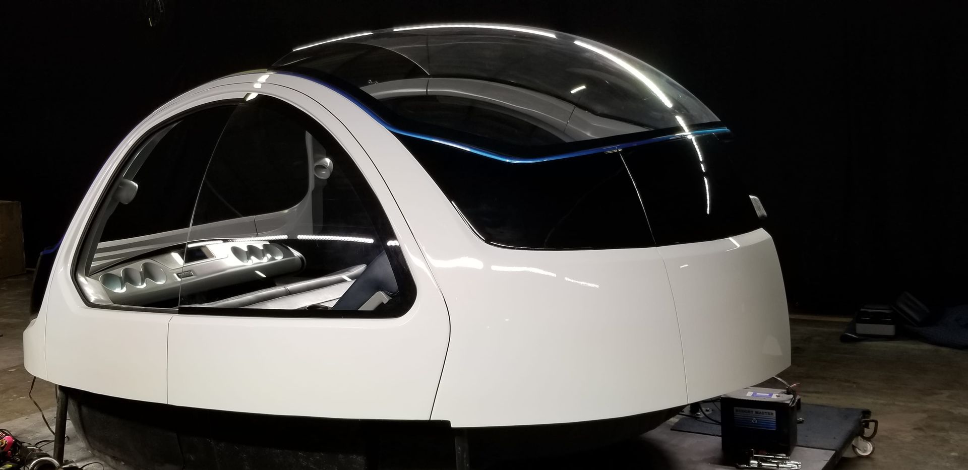 White and black aircraft cabin prototype with large windows, indoors.