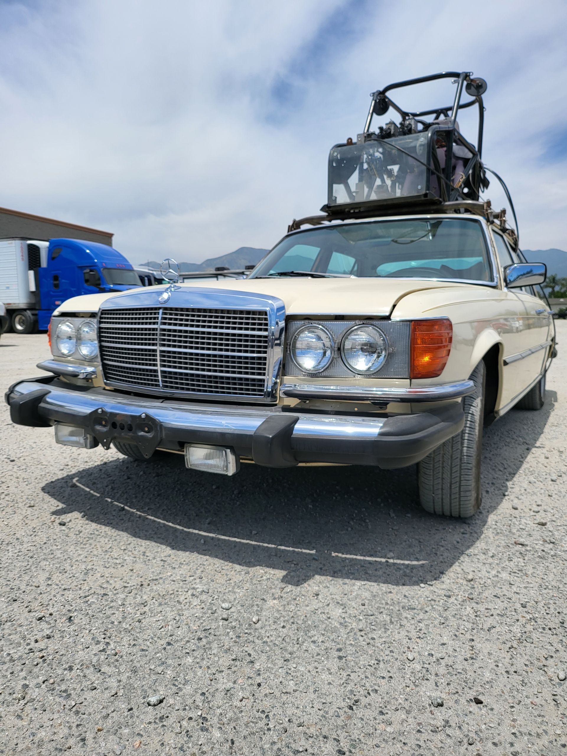 A car with a bicycle on top of it is parked in a gravel lot with installed pod rigs on it for film shooting.