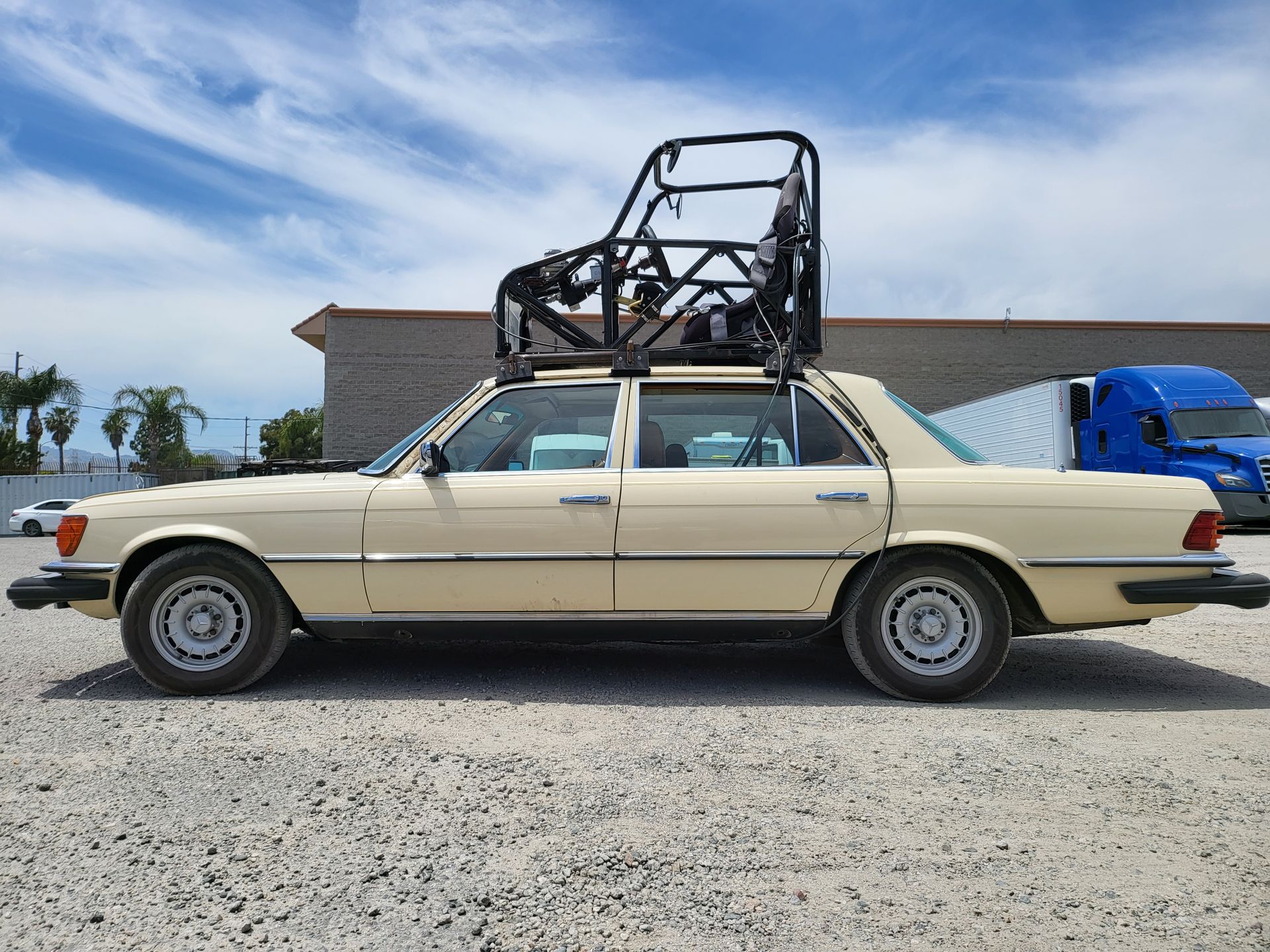 A car with a bicycle on top of it is parked in a gravel lot with installed pod rigs on it for film shooting.