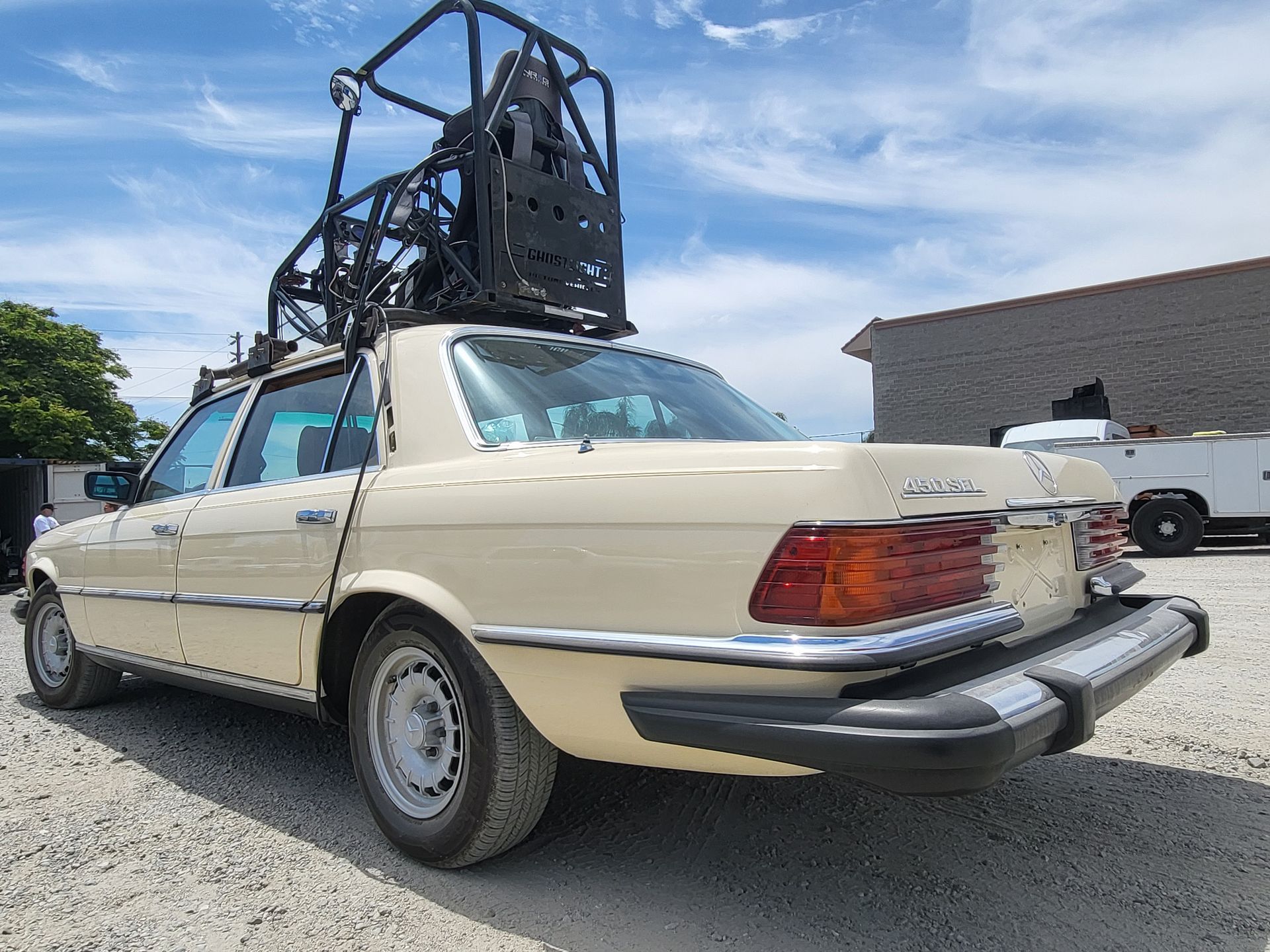 A car with a bicycle on top of it is parked in a gravel lot with installed pod rigs on it for film shooting.