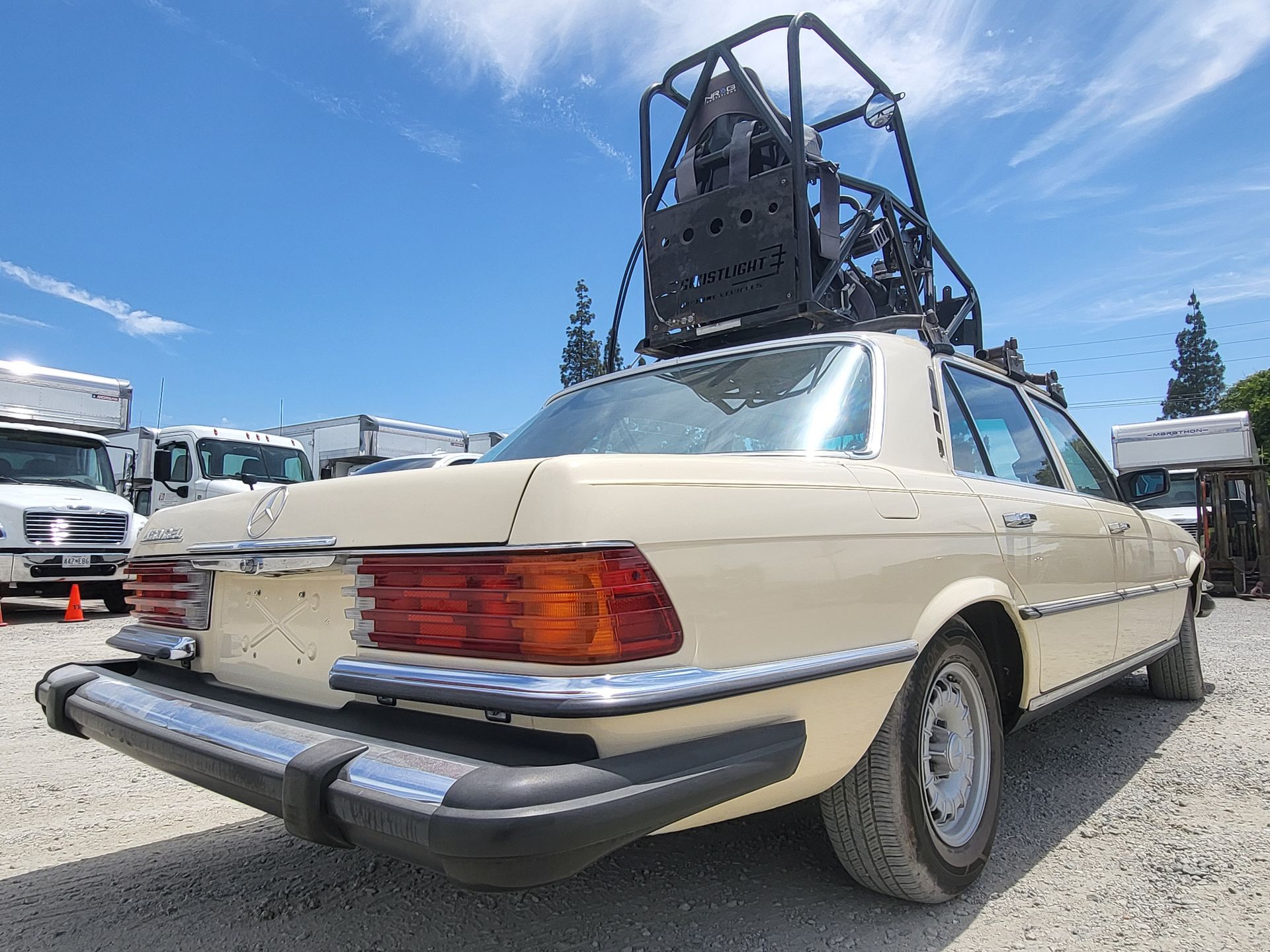 A car with a bicycle on top of it is parked in a gravel lot with installed pod rigs on it for film shooting.