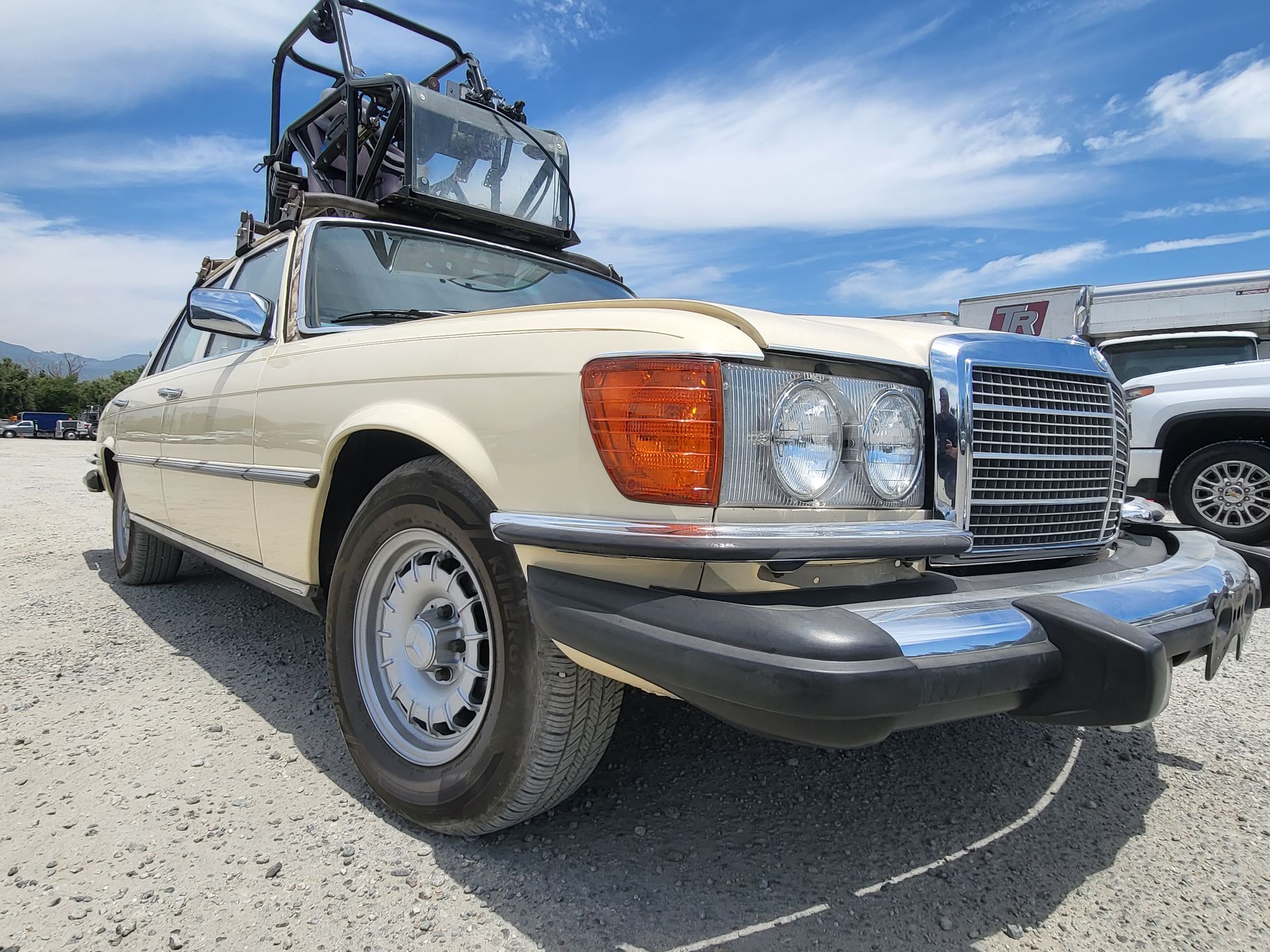 A car with a bicycle on top of it is parked in a gravel lot with installed pod rigs on it for film shooting.
