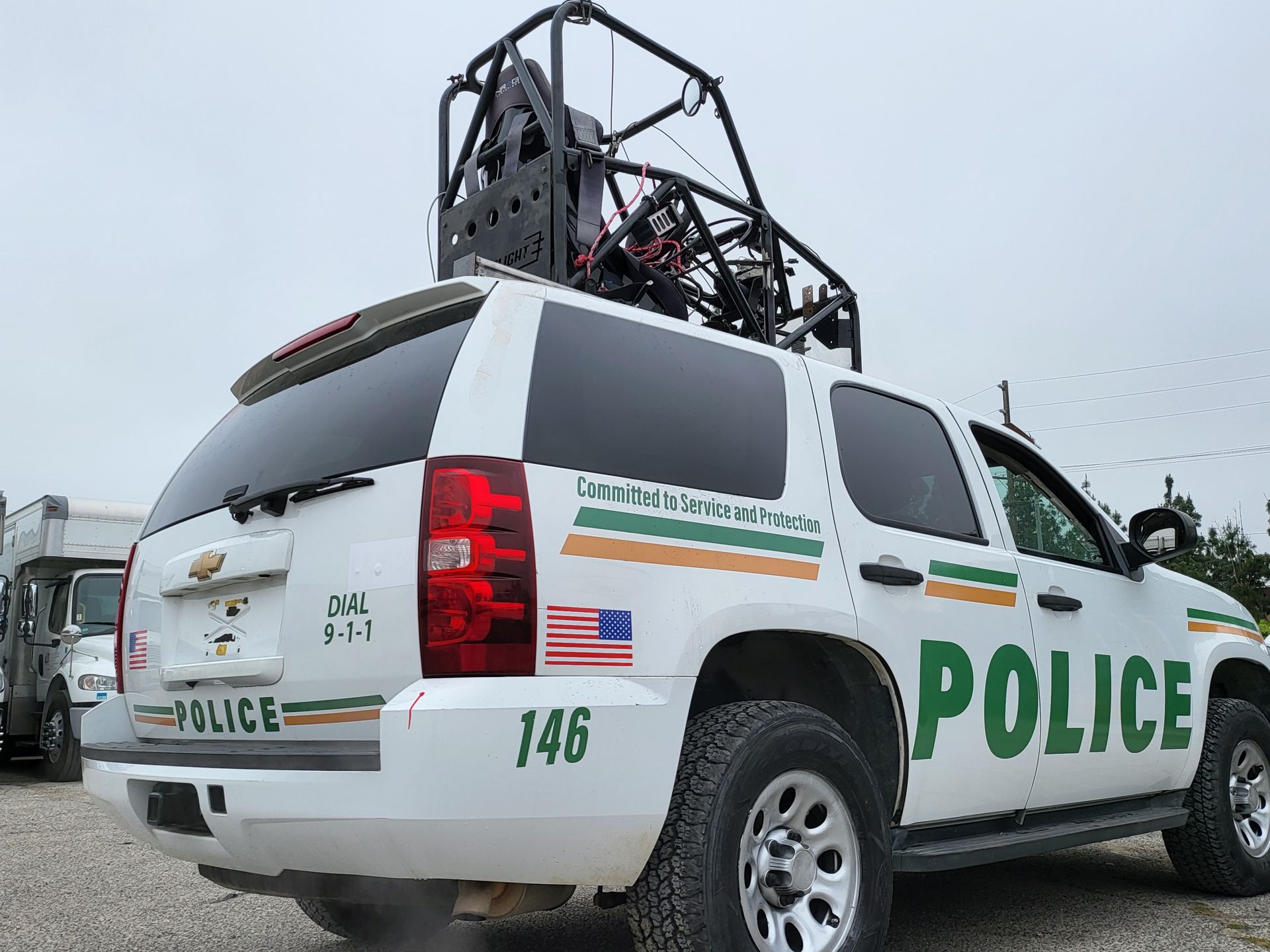 a white police suv is parked in a parking lot with pod rigs on top of it for film shooting