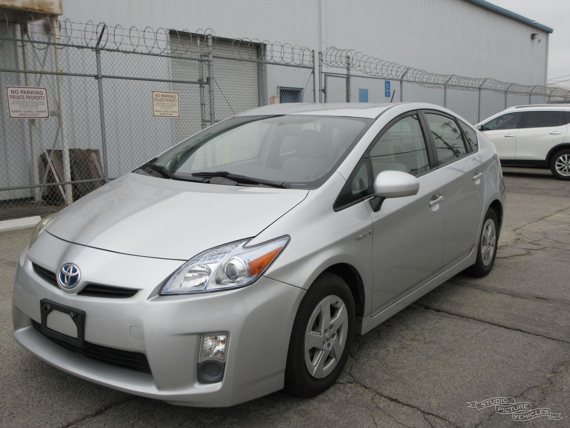 a silver toyota prius is parked in front of a fence and ready to install a pod rig for film shooting.