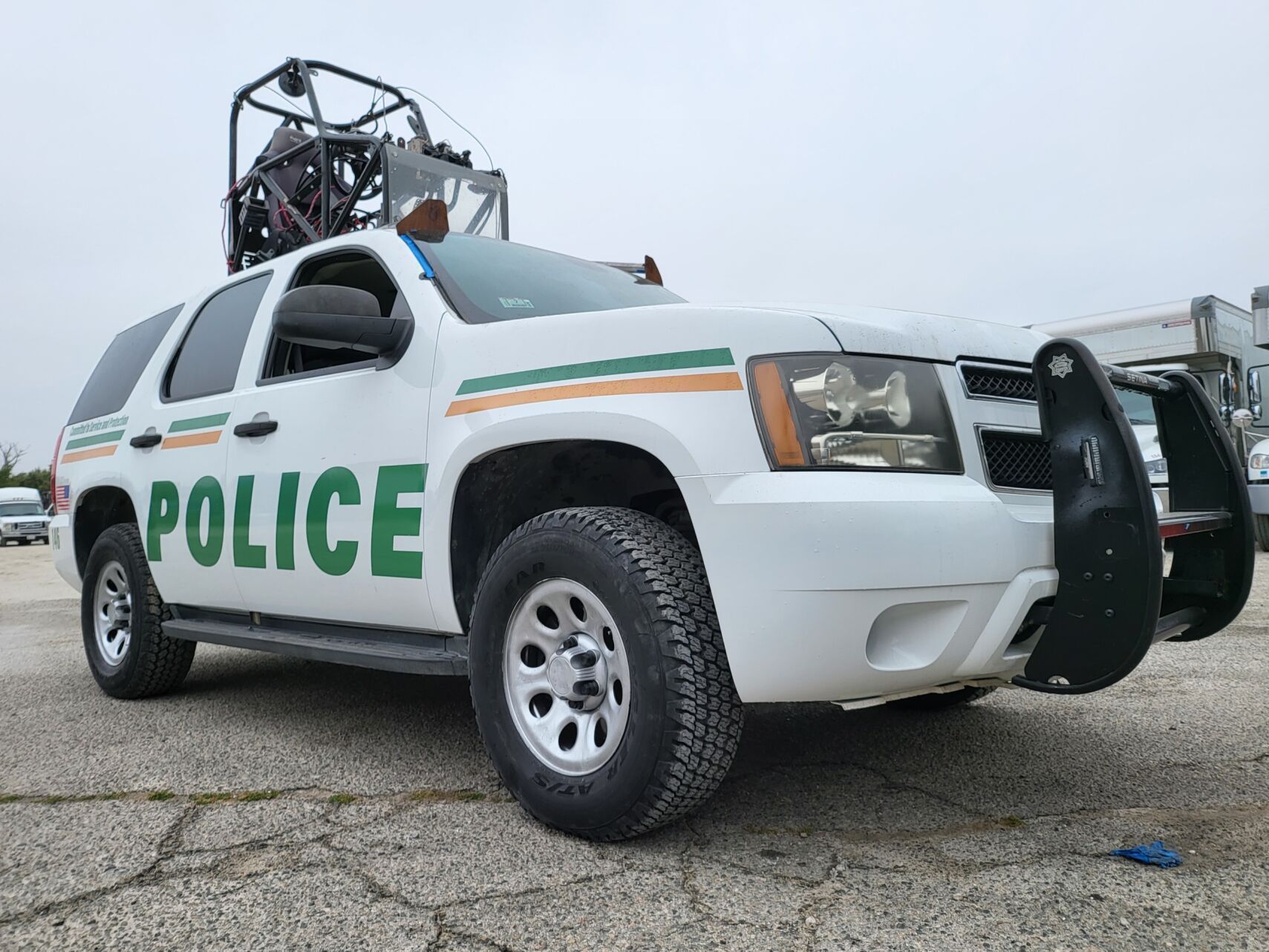 a white police suv is parked in a parking lot with pod rigs on top of it for film shooting