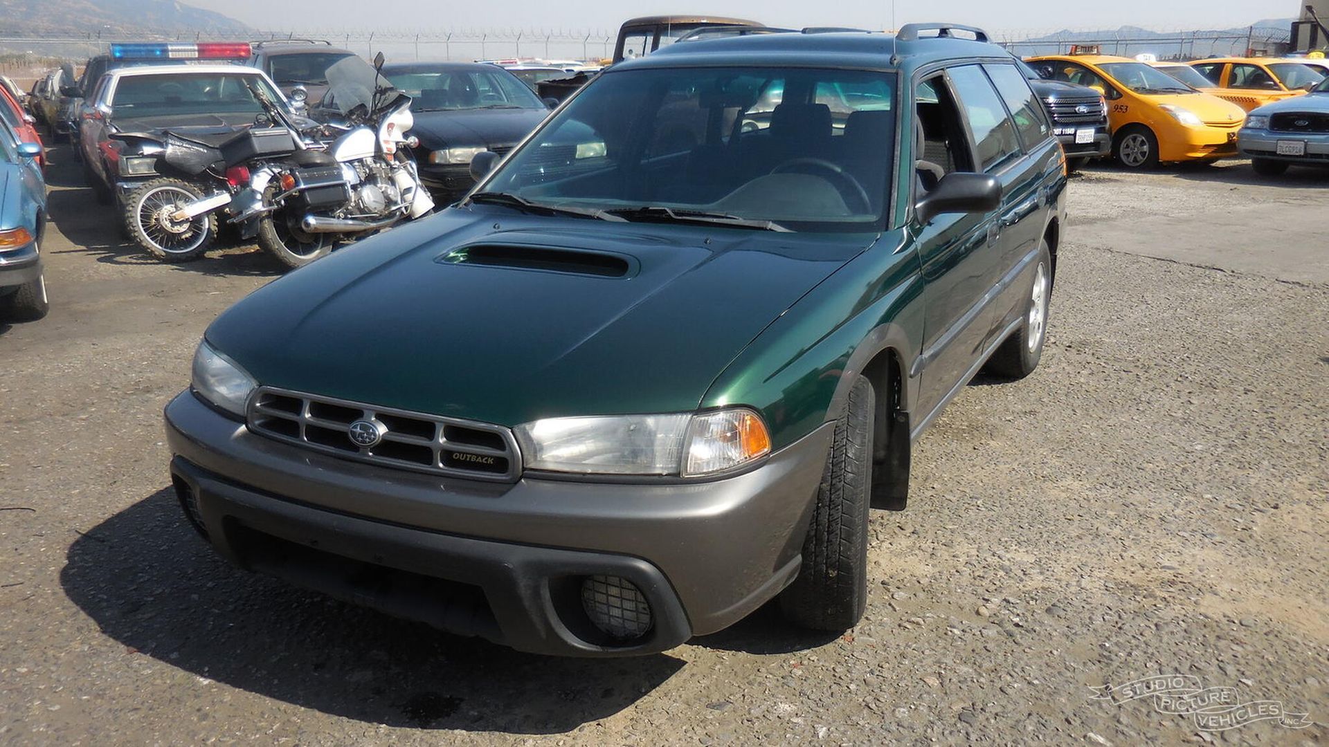 a green subaru station wagon is parked on the side of the road and ready to install a pod rig for film shooting.