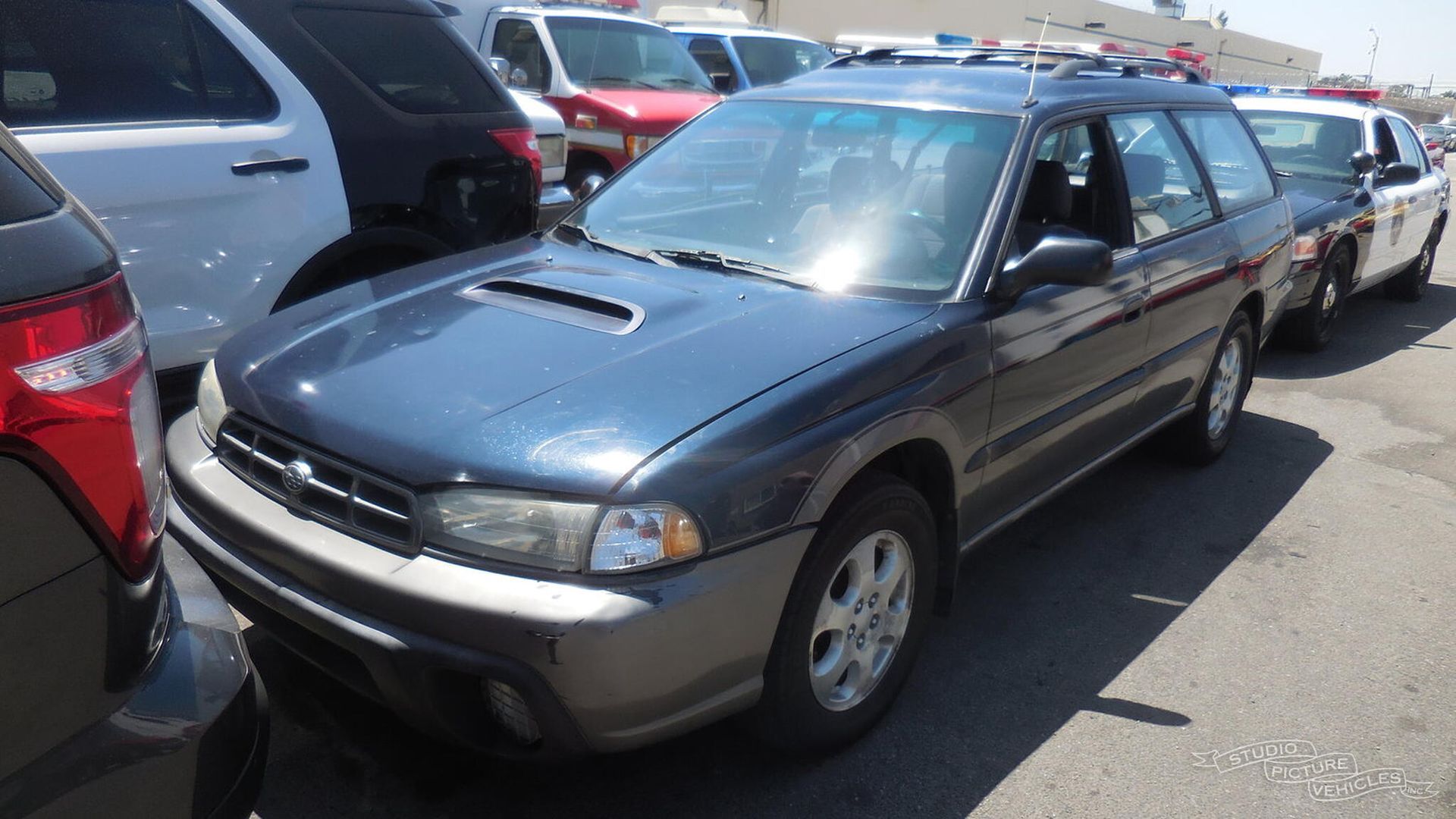 a green subaru station wagon is parked on the side of the road and ready to install a pod rig for film shooting.