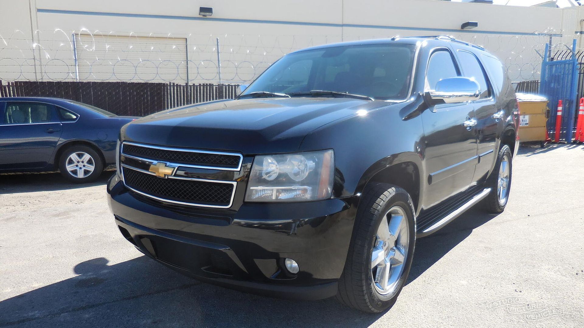 a black suv is parked in front of a fence and ready to install a pod rig for film shooting.