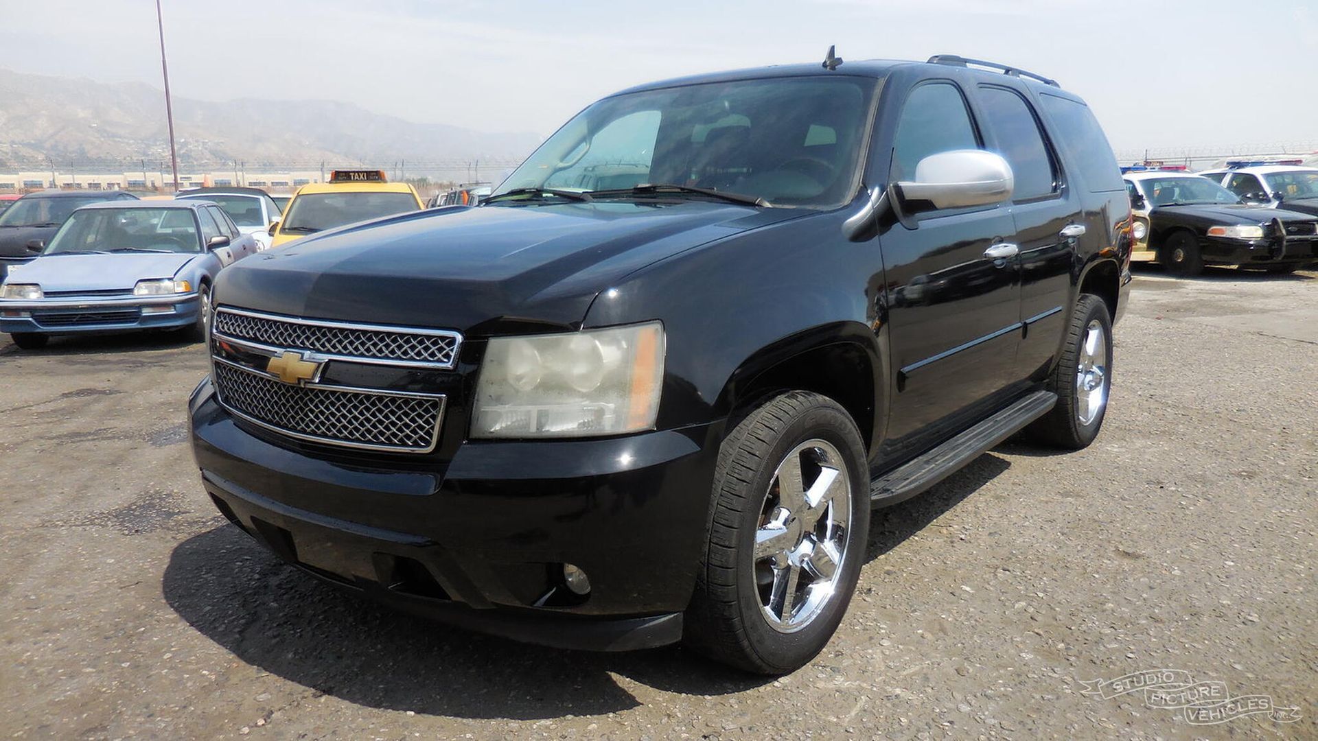 a black suv is parked in front of a fence and ready to install a pod rig for film shooting.