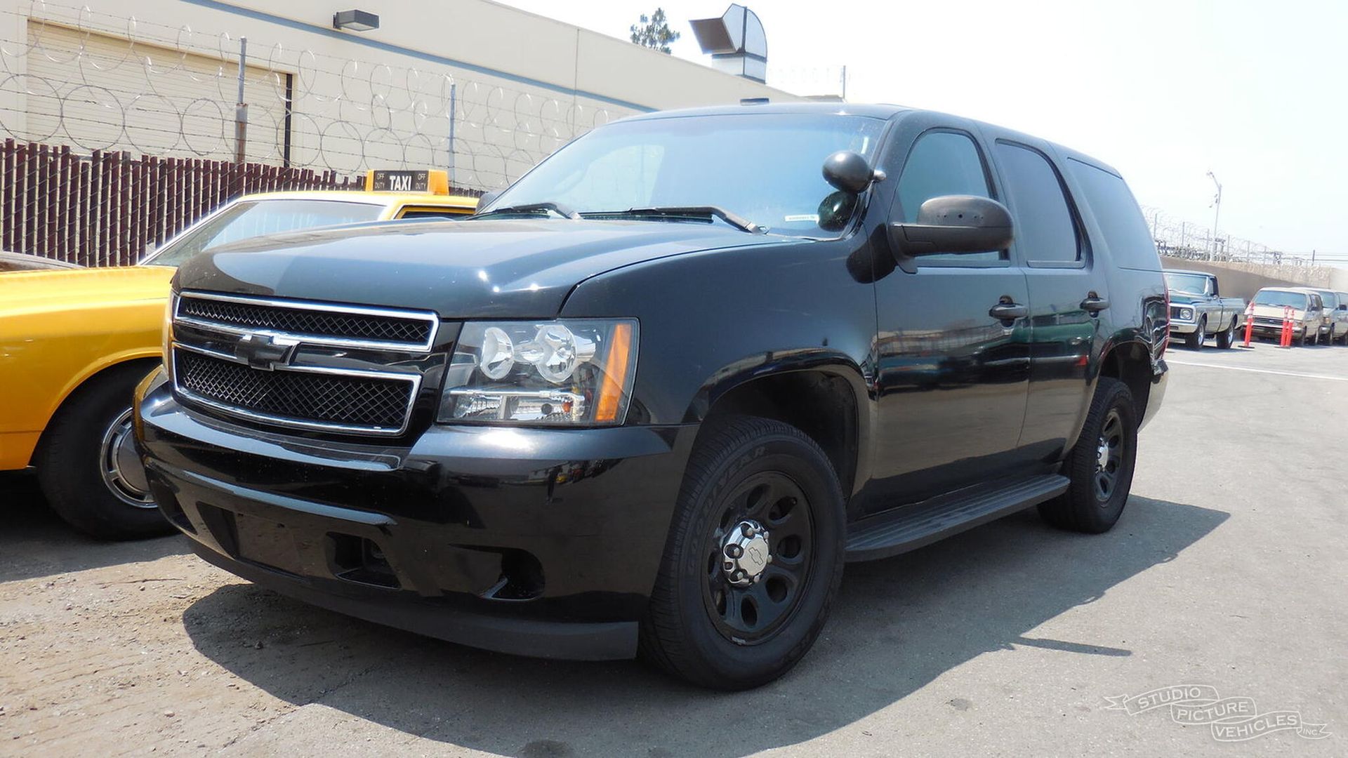 a black suv is parked in front of a fence and ready to install a pod rig for film shooting.