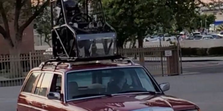 A red car equipped with a camera mounted on its roof, ready for capturing images or video.