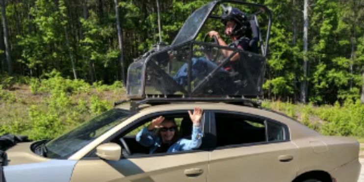  A man driving a car with a passenger seated in the back, focused on the road ahead.