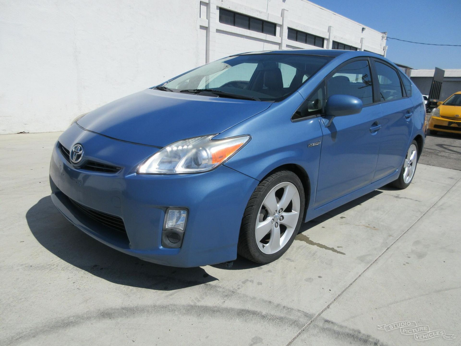a blue toyota prius is parked in a parking lot and ready to install a pod rig for film shooting.
