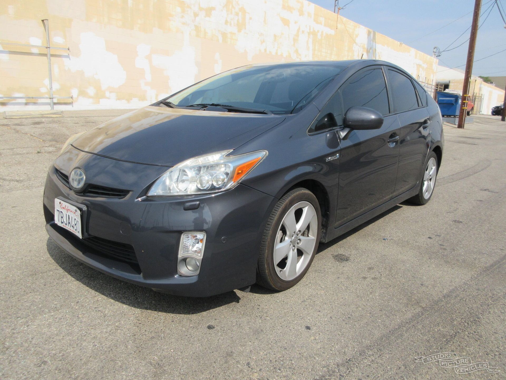 a black toyota prius is parked in front of a building and ready to install a pod rig for film shooting.