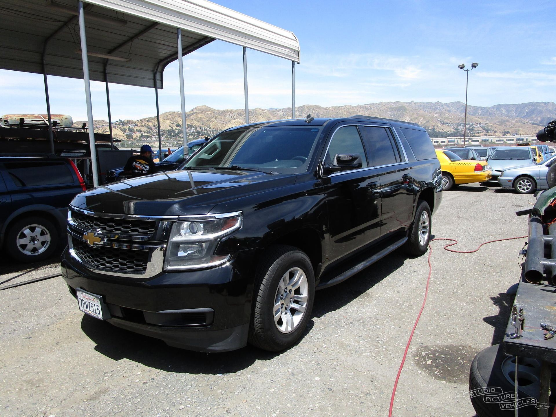 a black suv is parked in front of a fence and ready to install a pod rig for film shooting.