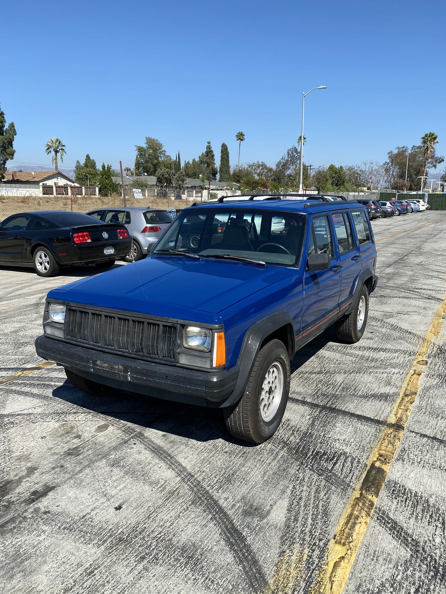 a blue jeep cherokee is parked in a parking lot 