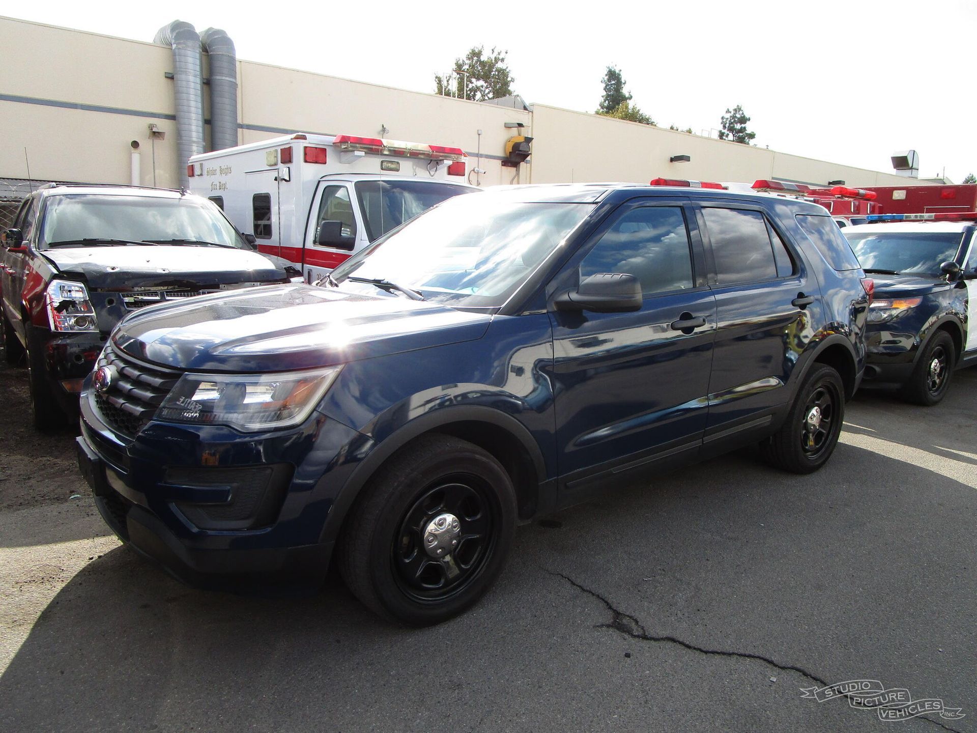 A blue police car is parked in front of a building and ready to install a pod rig for film shooting.