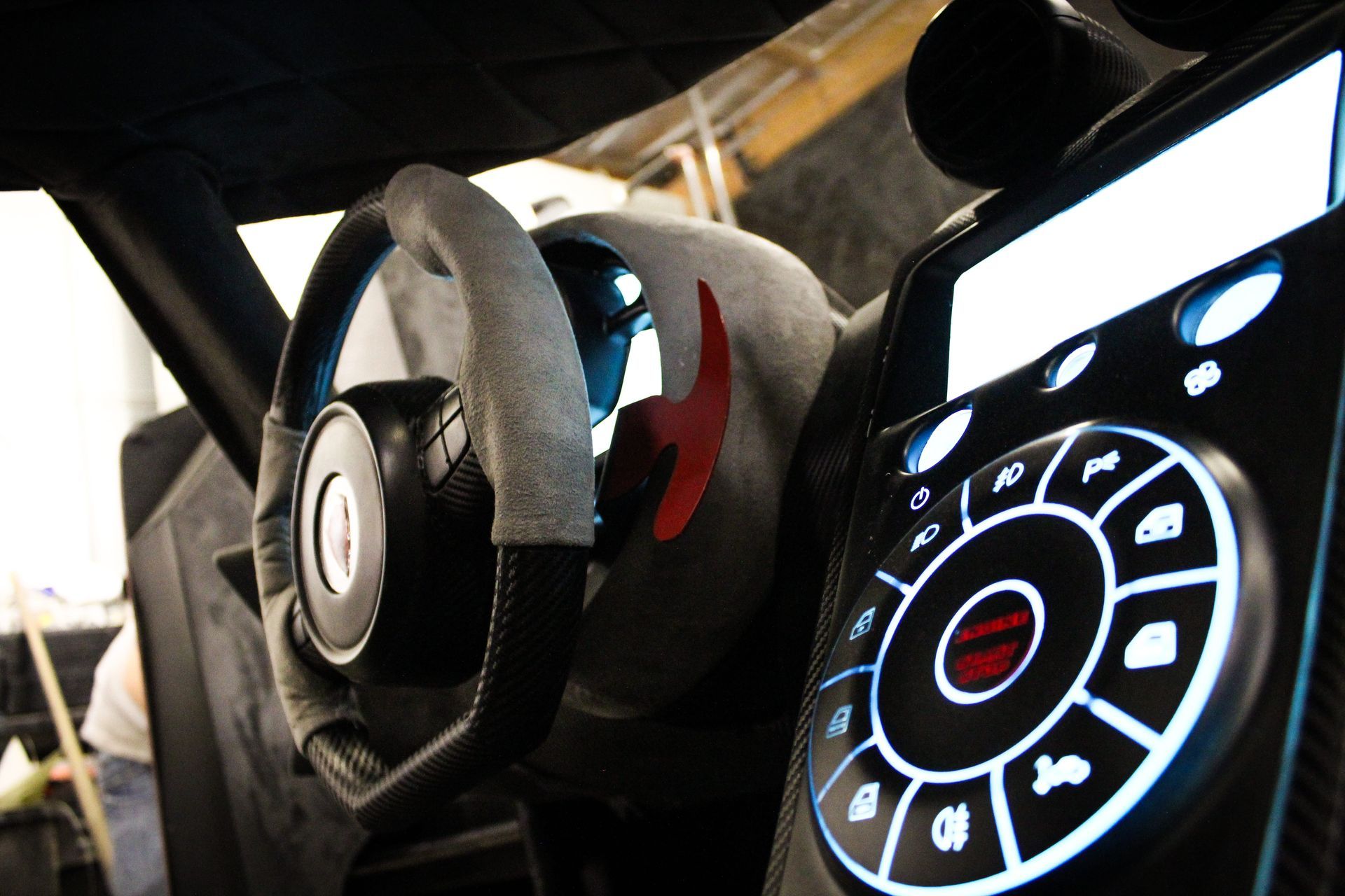 Need for Speed car - Close-up of a car's interior: steering wheel, control panel with circular dial, black and gray color scheme.