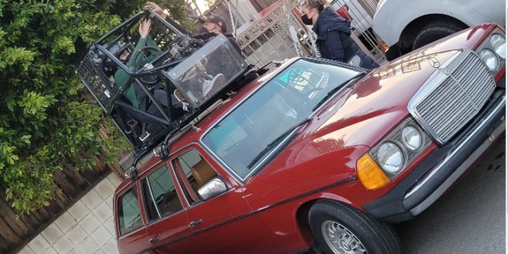 A red car featuring a roof rack, parked against a clear blue sky, showcasing its sporty design and practicality.