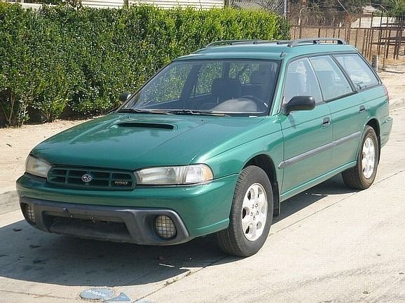 a green subaru station wagon is parked on the side of the road and ready to install a pod rig for film shooting.