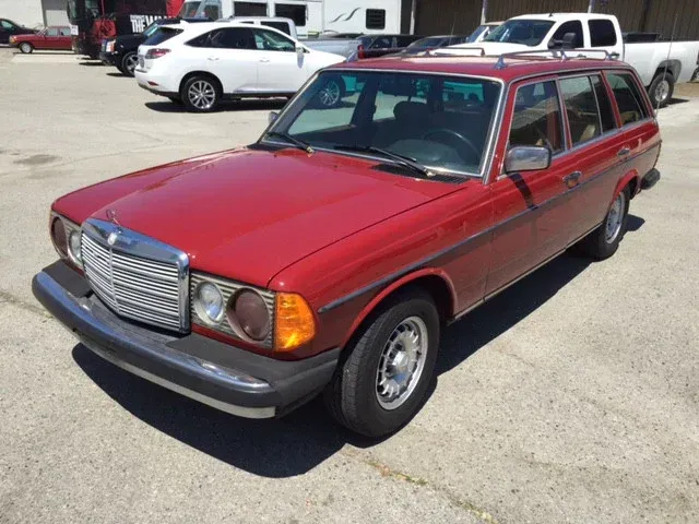 a red mercedes station wagon is parked in a parking lot and ready to install a pod rig for film shooting.
