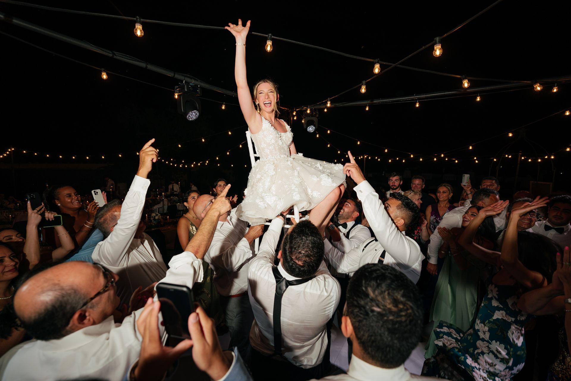 Bride lifted by guests at Villa del Balbianello Lake Como during luxury wedding party in Italy