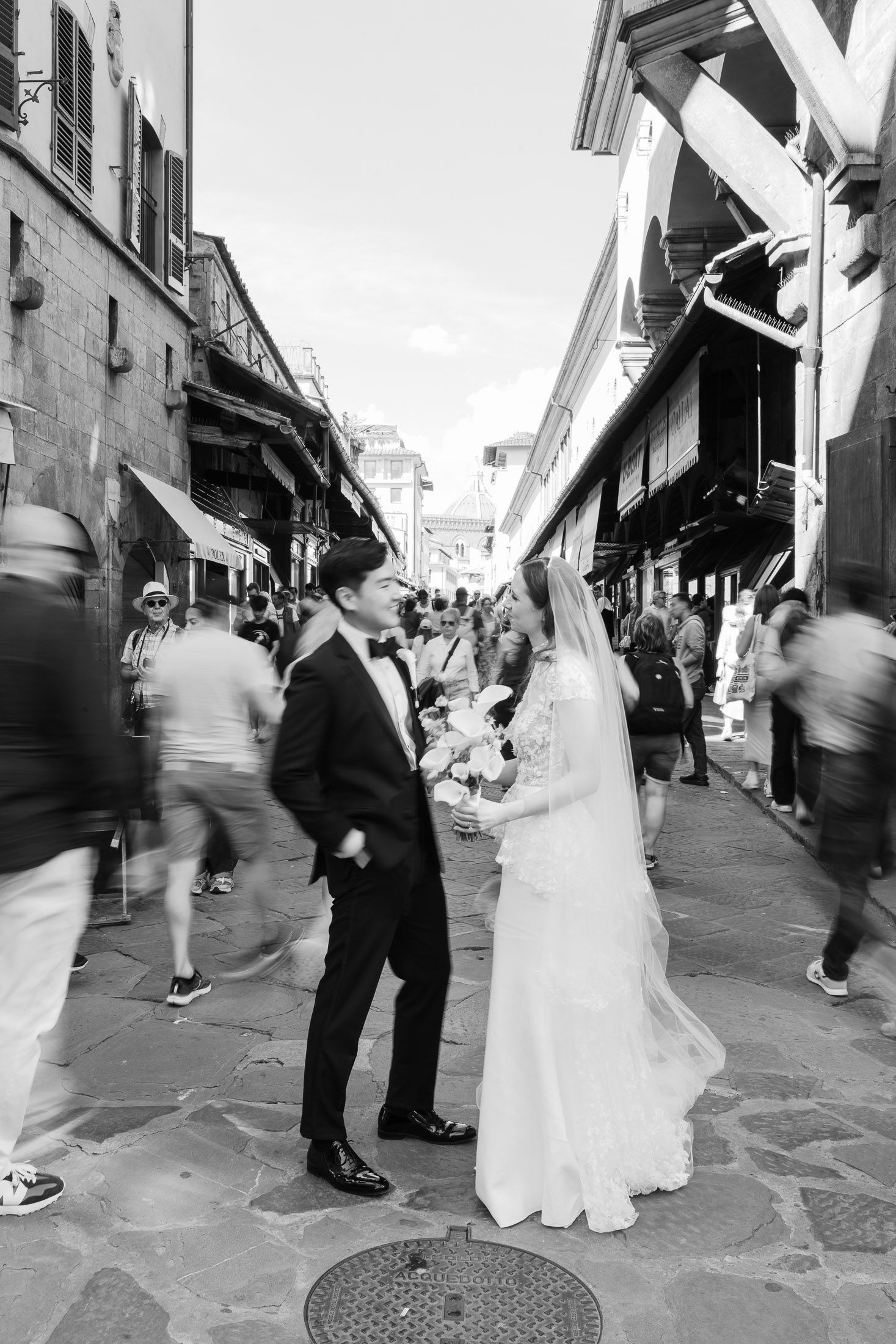 Bride and groom walking in Florence during wedding day captured in editorial black and white style