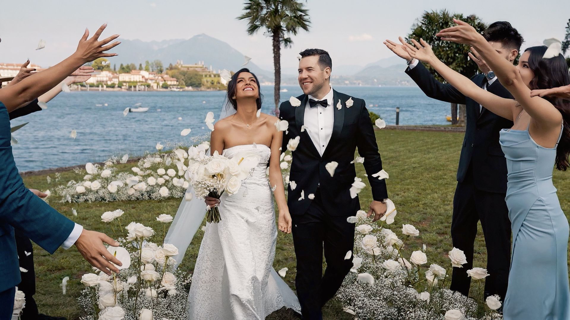 Bride and groom walking by Lake Como at Villa Palazzo Aminta during luxury wedding ceremony with flower petals