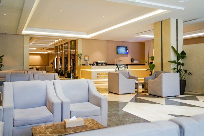 Modern hotel lobby with white sofas, warm wood accents, and reception desk in the background