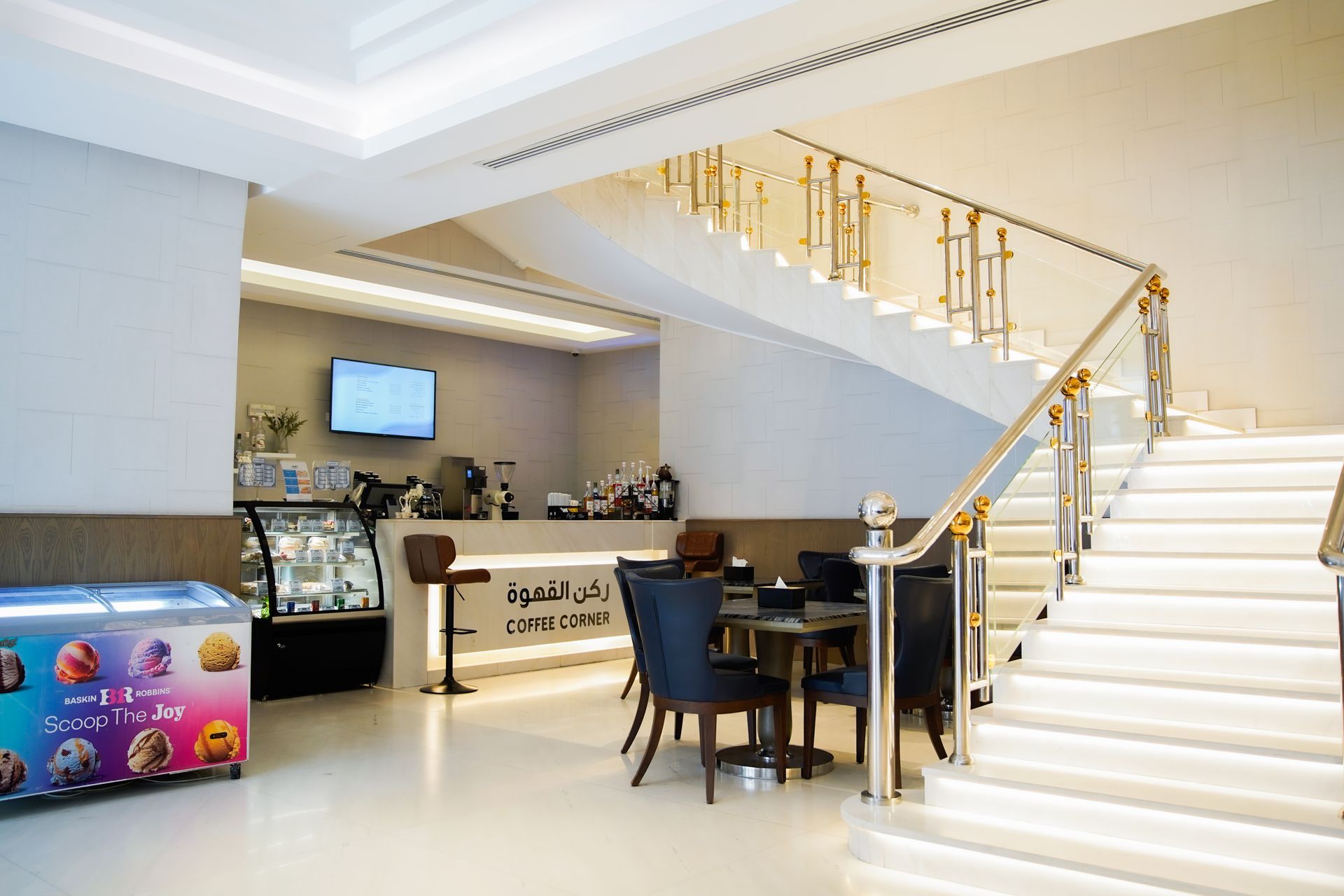 Bright lobby with white staircase, gold railing, reception desk, and seating area