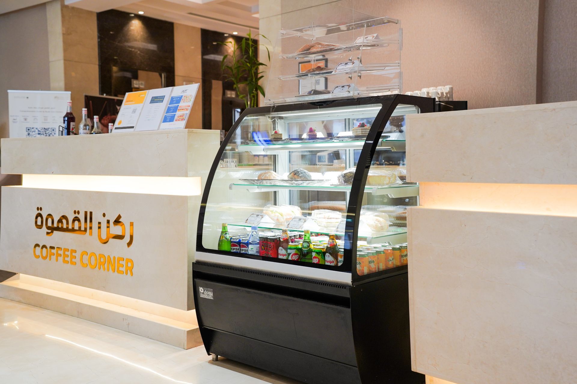 Modern coffee shop counter with display case and Arabic Coffee Corner signage