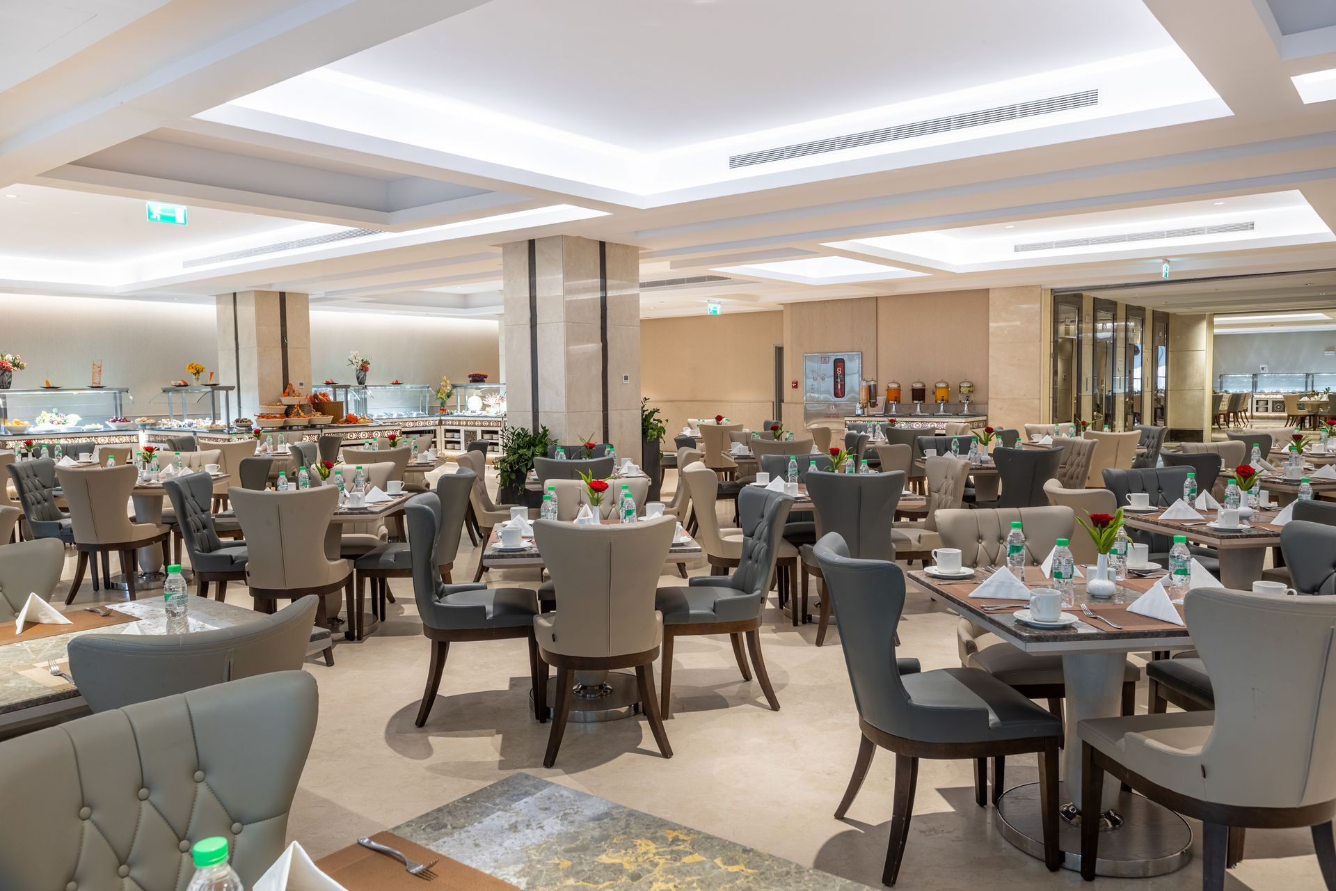 Elegant dining room with set tables, gray chairs, and soft ceiling lighting