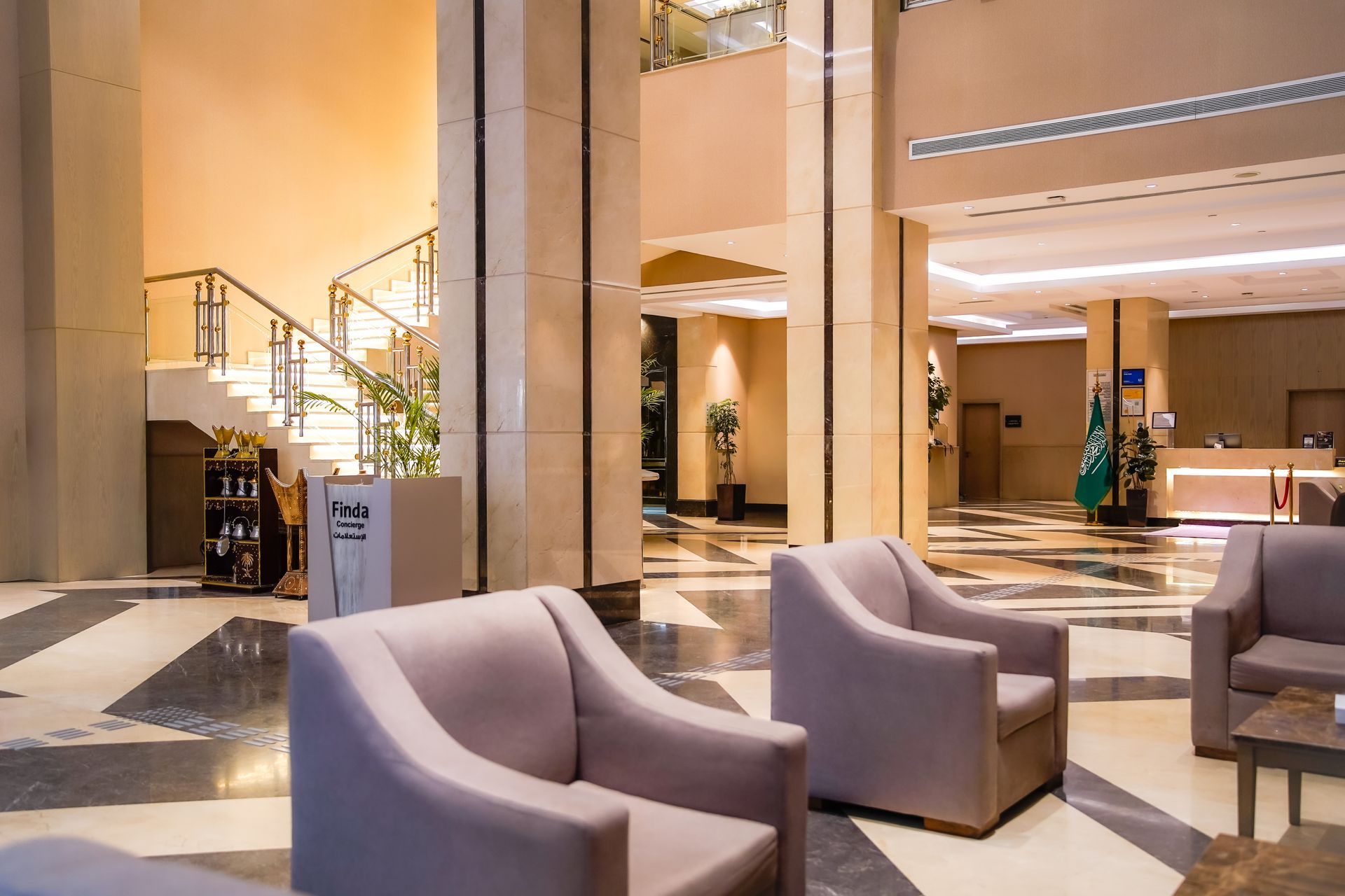 Modern hotel lobby with lounge chairs, marble floors, and warm lighting