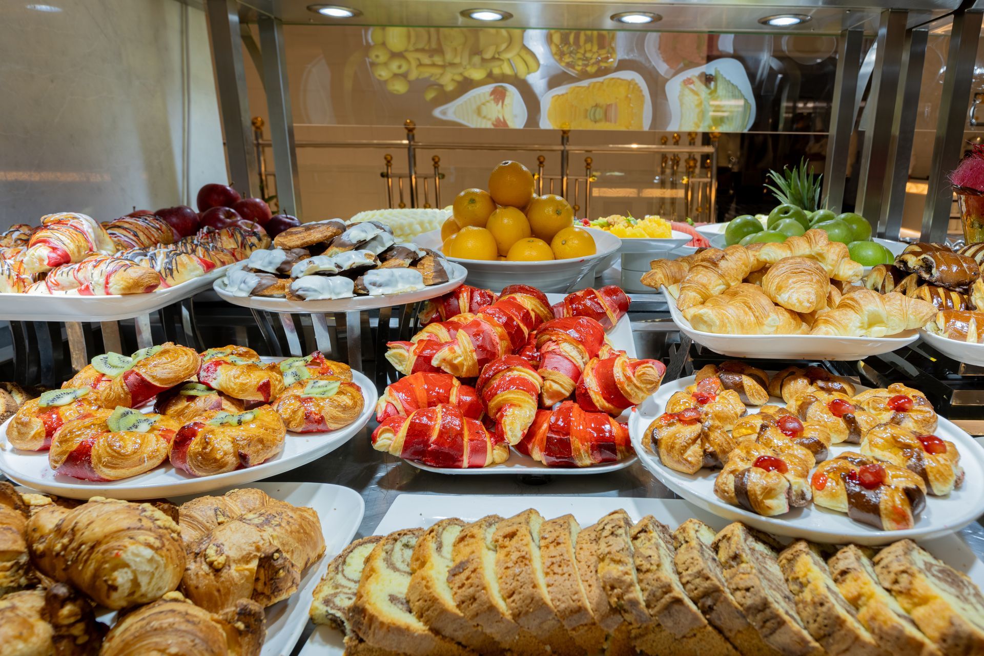 Assorted pastries and fruit displayed on a buffet table in a bright dining area