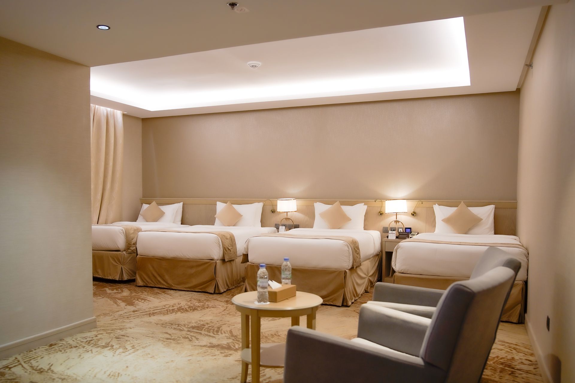 Cozy lounge with multiple white sofas, armchairs, and warm recessed lighting in a neutral-toned room
