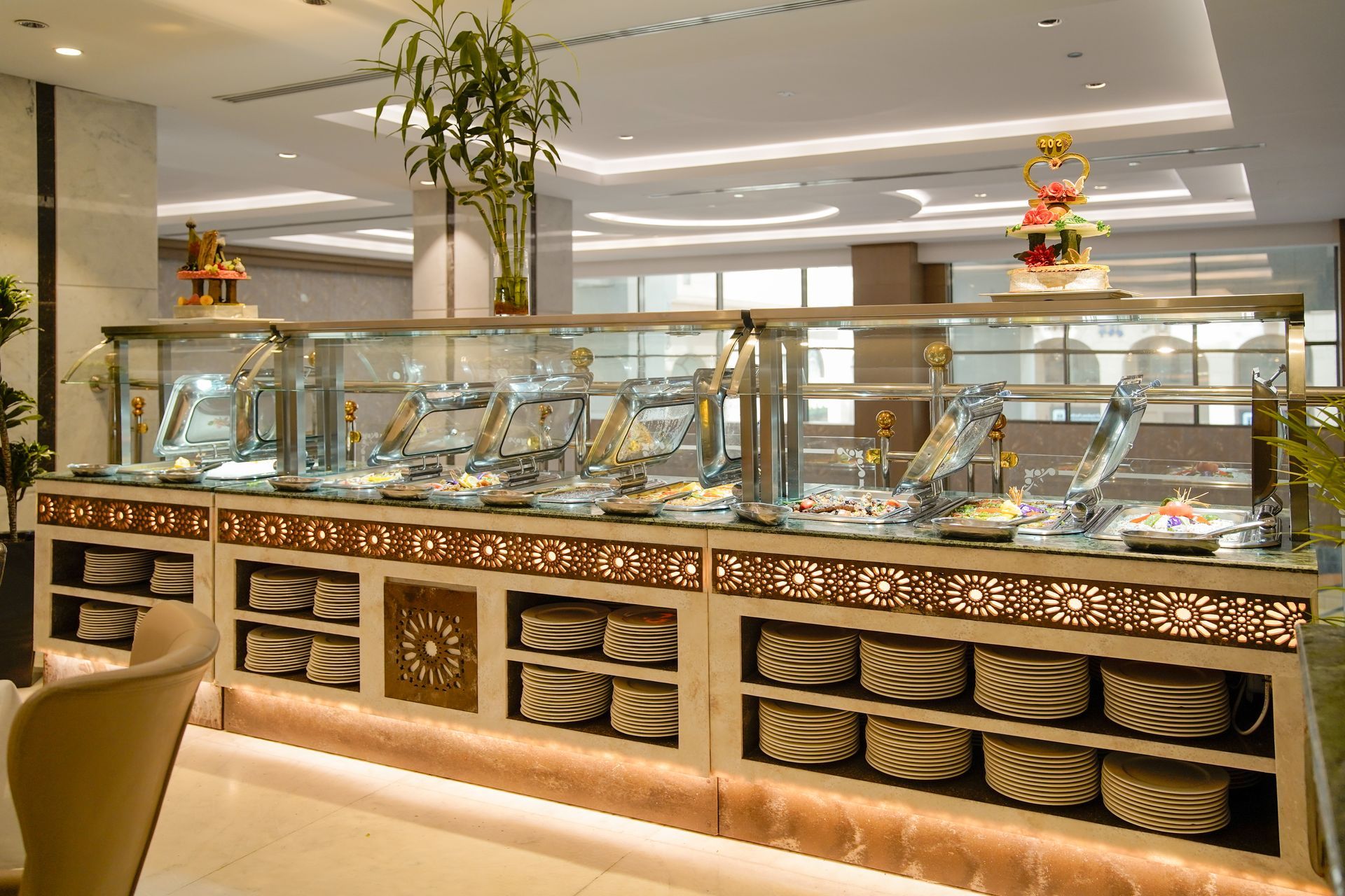Elegant buffet counter with glass covers and neatly arranged dishes in a bright restaurant interior