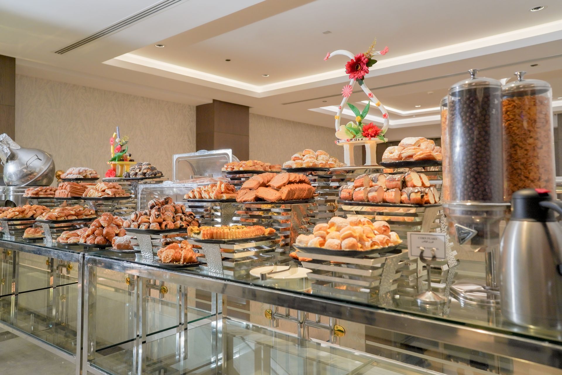 Buffet counter with trays of pastries and desserts in a bright hotel dining area