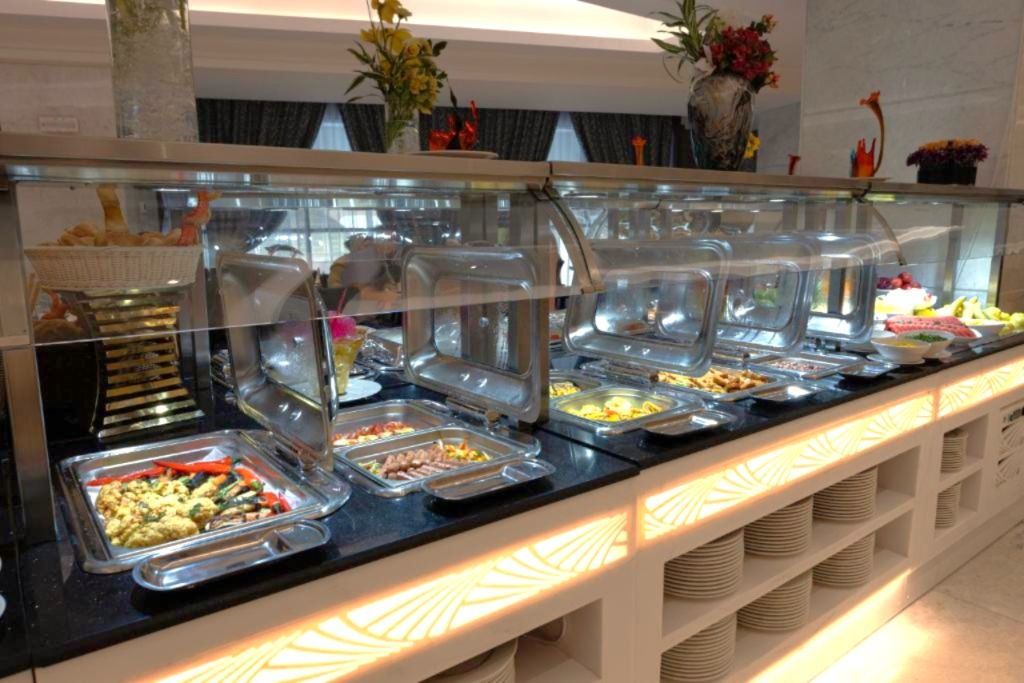 Buffet counter with covered hot dishes and a lit display of prepared food in a restaurant