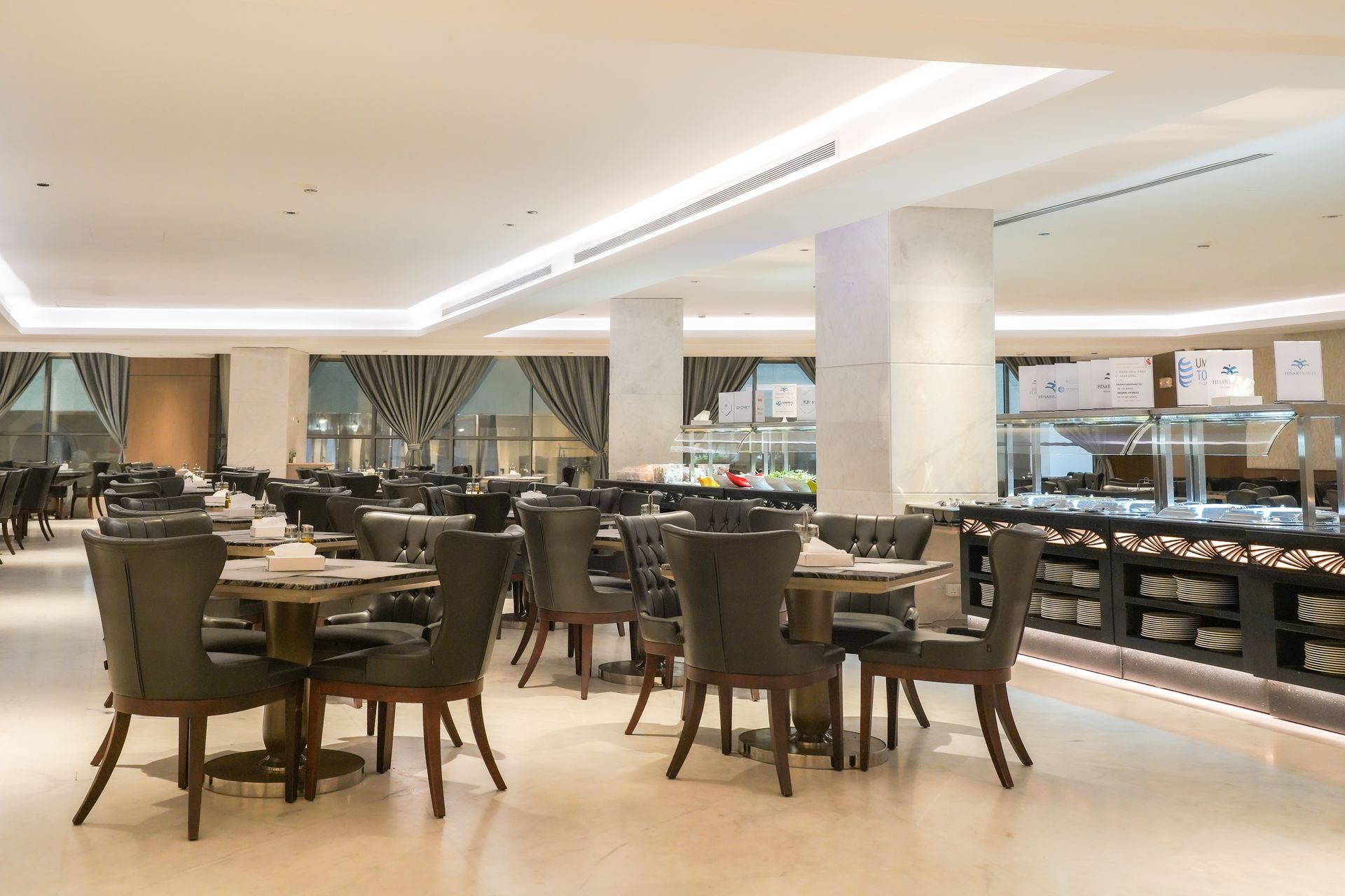 Upscale restaurant dining room with dark chairs, set tables, and warm lighting