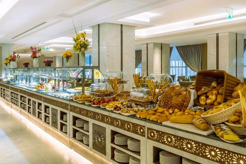 Elegant hotel buffet display with breads and pastries under glass in a bright dining hall