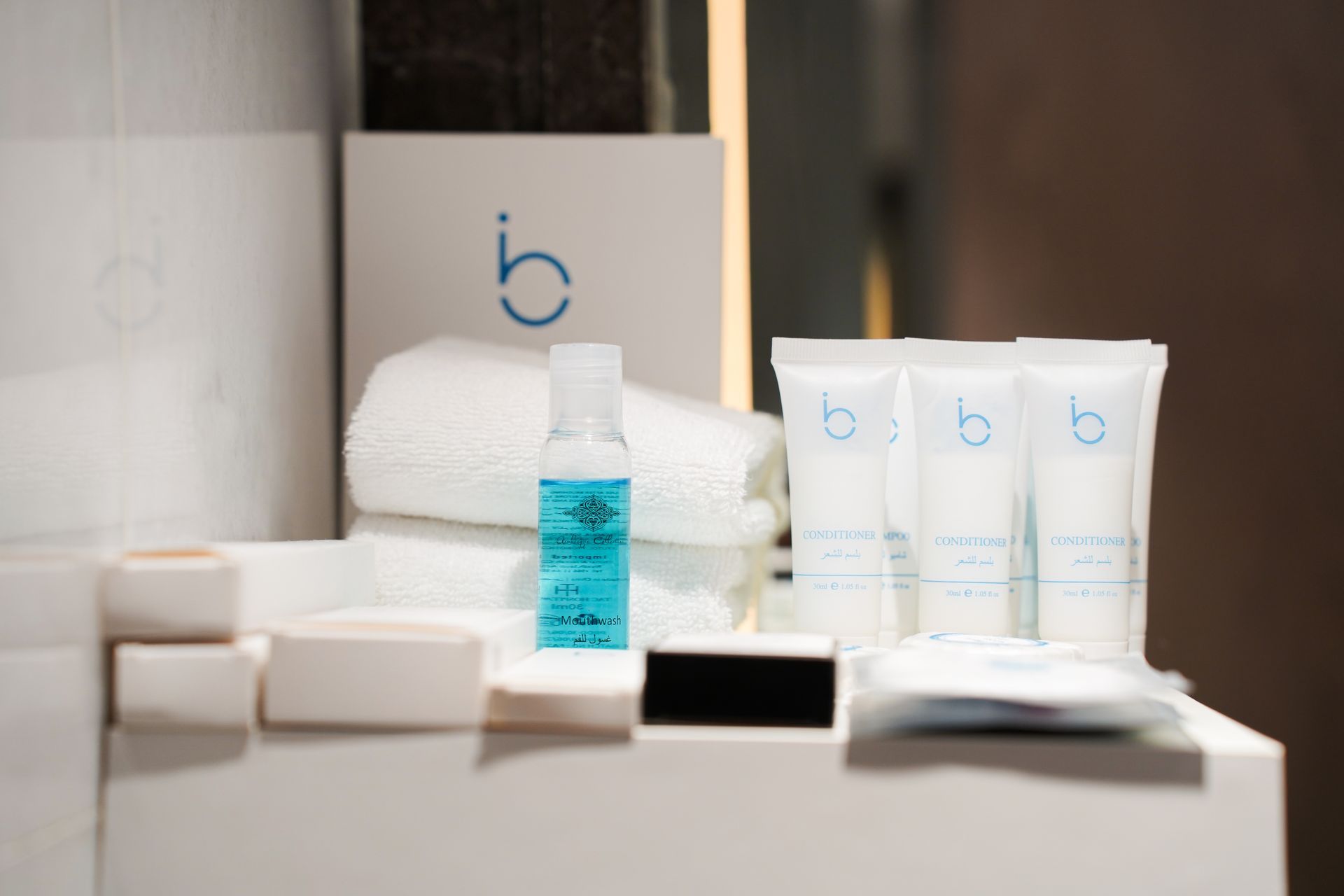 Spa product display with white containers, blue bottles, towels, and a box in a soft-lit setting