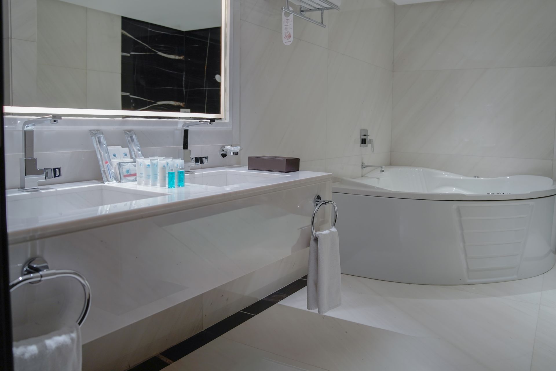 Modern bathroom with white tub, large mirror, and sink countertop with toiletries