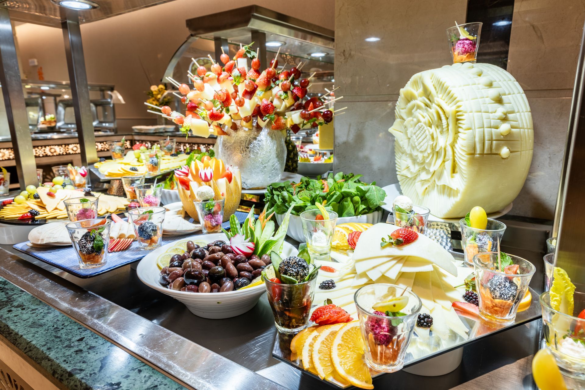 Colorful buffet dessert display with fruit, pastries, and a large decorative cream pastry arrangement