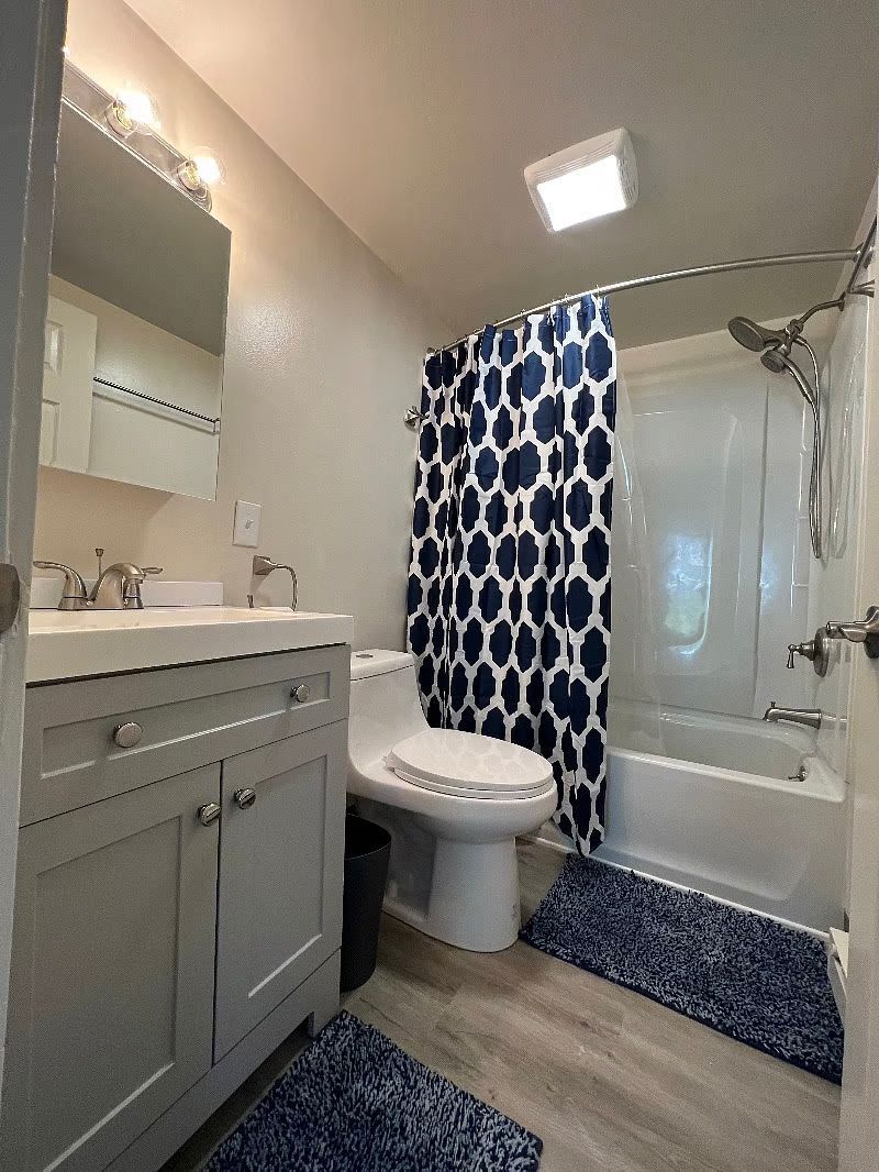A bathroom with a toilet , sink , bathtub and shower curtain.