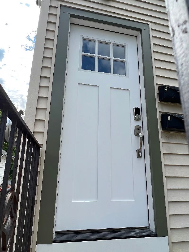 A white door with a green trim is on the side of a house.