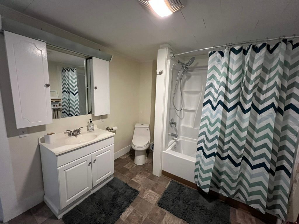 A bedroom with a bed , desk , chair and rug.