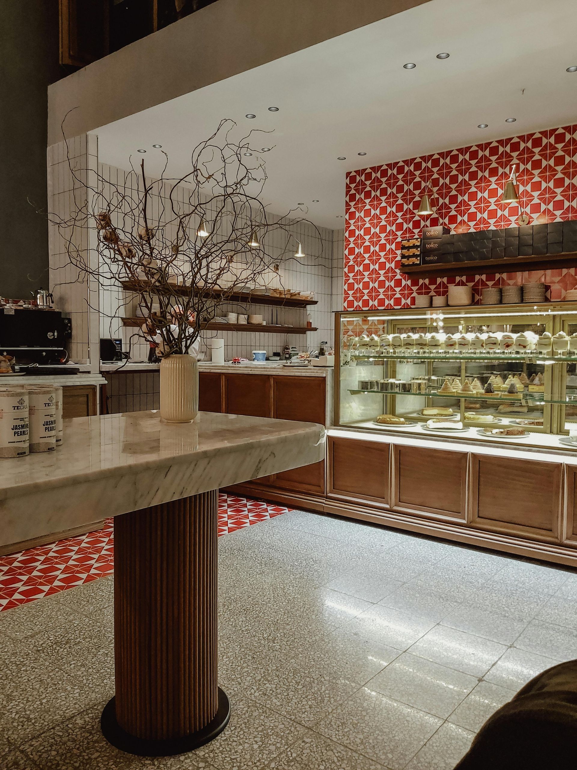 A kitchen with white cabinets , stainless steel appliances , wooden floors and a large island with chairs.