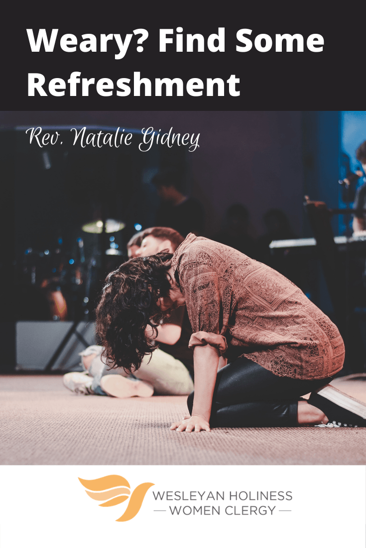 Picture of Latina young woman kneeling in worship on carpeted floor in a worship room.